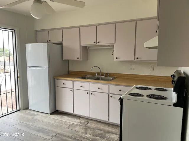a kitchen with a refrigerator and white cabinets