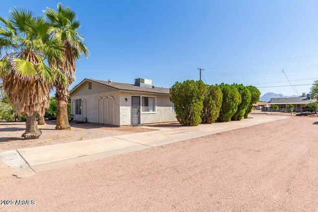 a front view of a house with a yard and palm trees