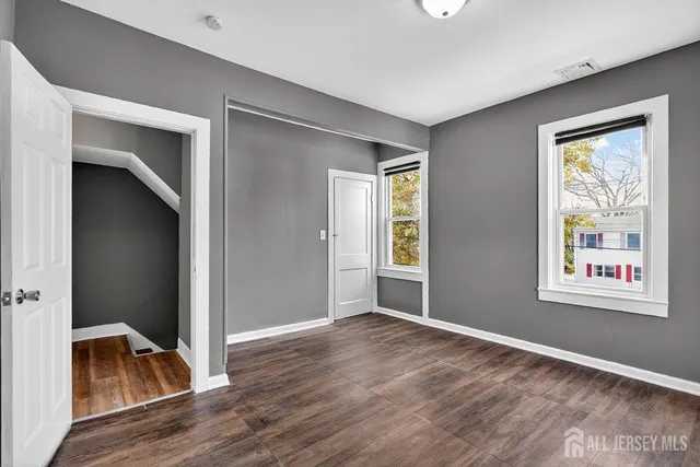 an empty room with wooden floor windows and hallway
