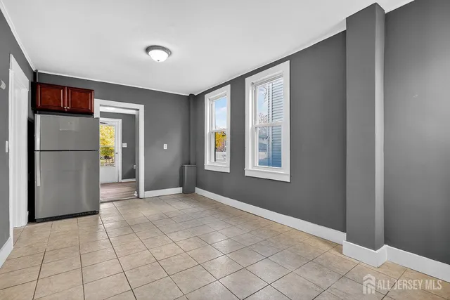 a view of an empty room with window and refrigerator