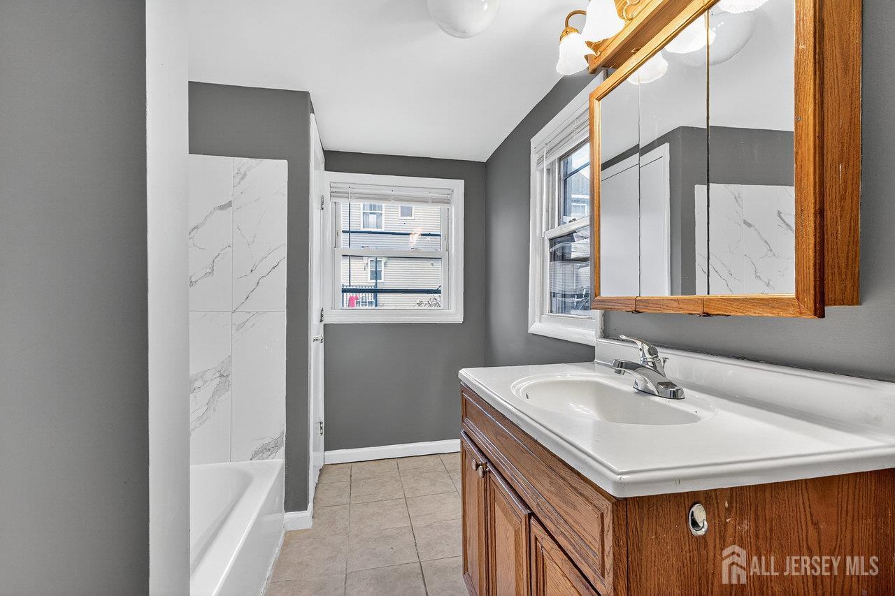 309-311 Pulaski Street Dunellen, NJ 08812 - Photo 6 of 24 a bathroom with a sink a vanity and a mirror