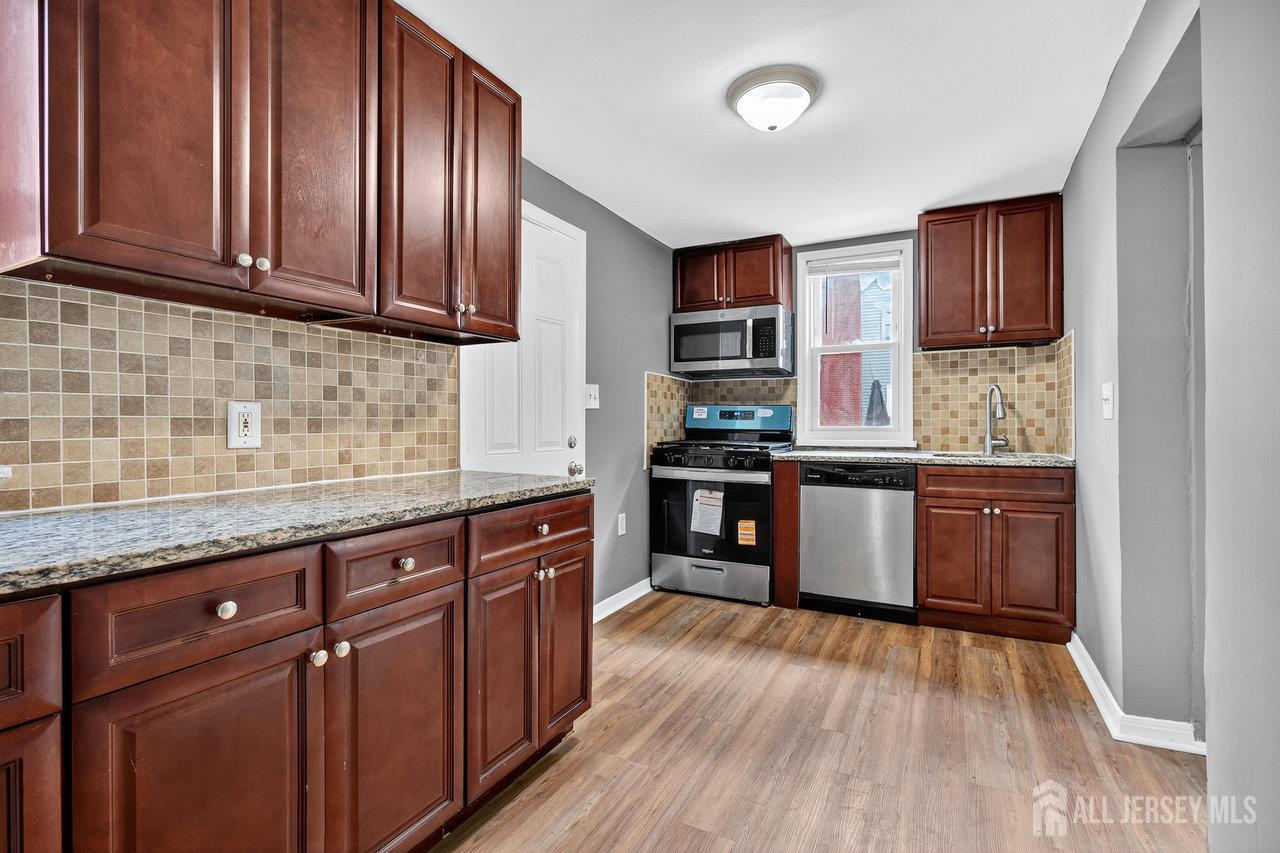 309-311 Pulaski Street Dunellen, NJ 08812 - Photo 7 of 24 a kitchen with stainless steel appliances granite countertop wooden cabinets a sink and dishwasher with wooden floor