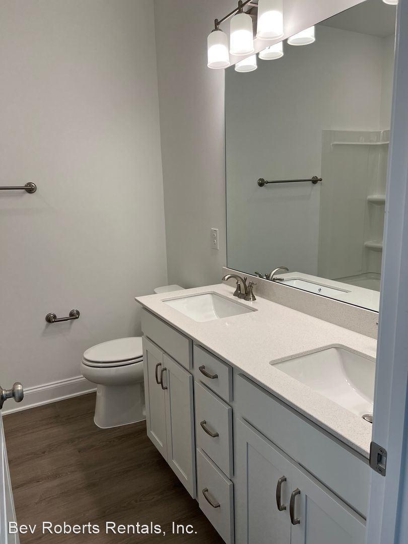 2104 Stegemann Street Apex, NC 27502 - Photo 19 of 29 a bathroom with a granite countertop toilet a sink and a mirror