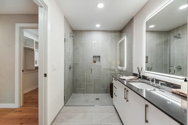 a bathroom with a double vanity sink and mirror with shower