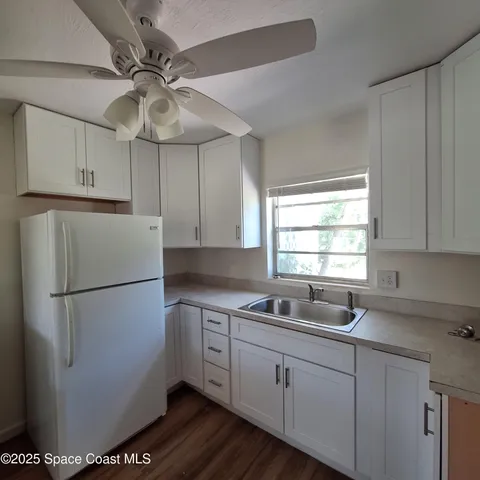 a white kitchen with a refrigerator a sink and dishwasher with white cabinets