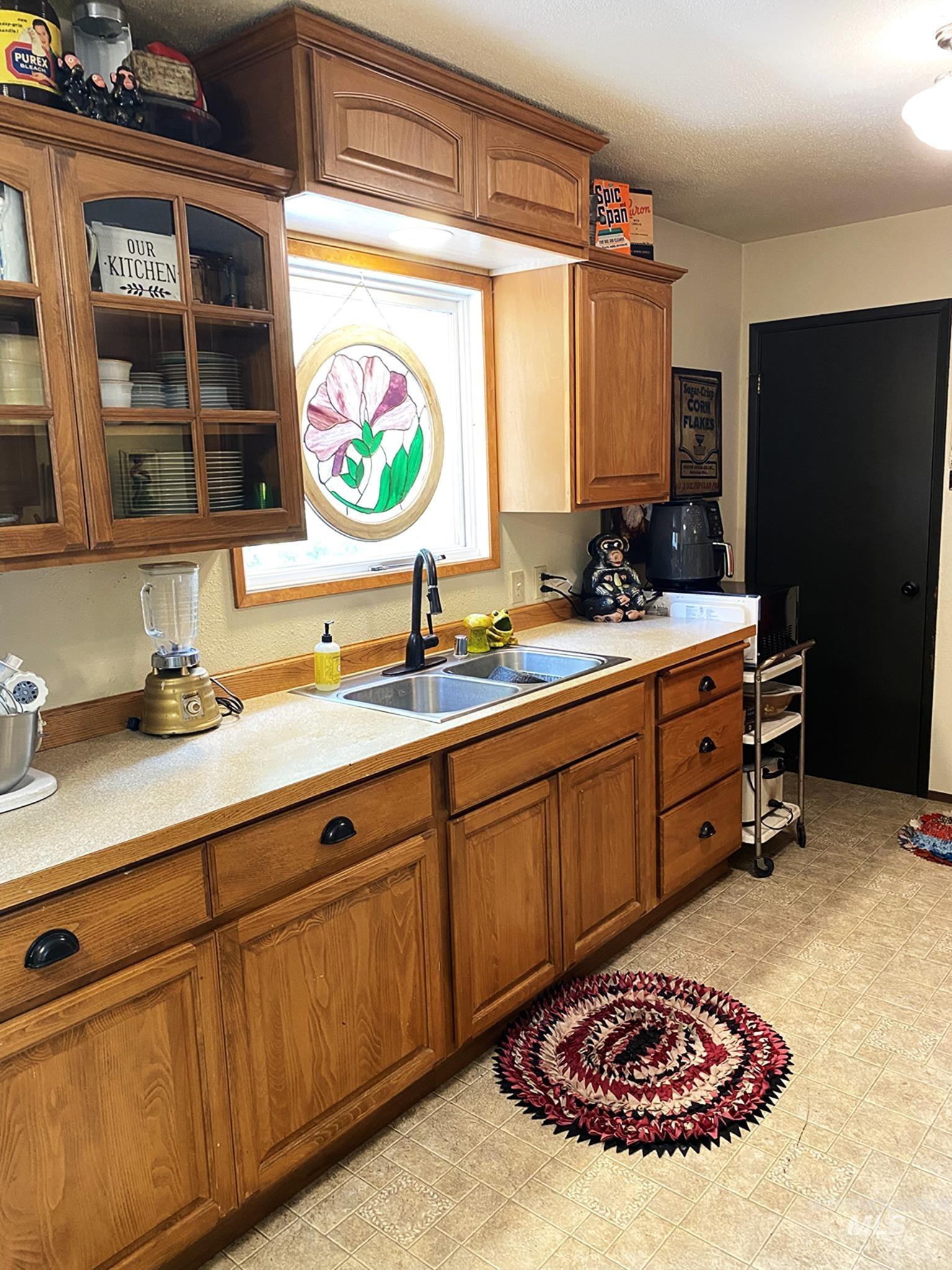 138 Timberline Drive Pierce, ID 83546 - Photo 7 of 28 Kitchen with light countertops, wood finish cabinets, glass insert cabinets, and a textured ceiling
