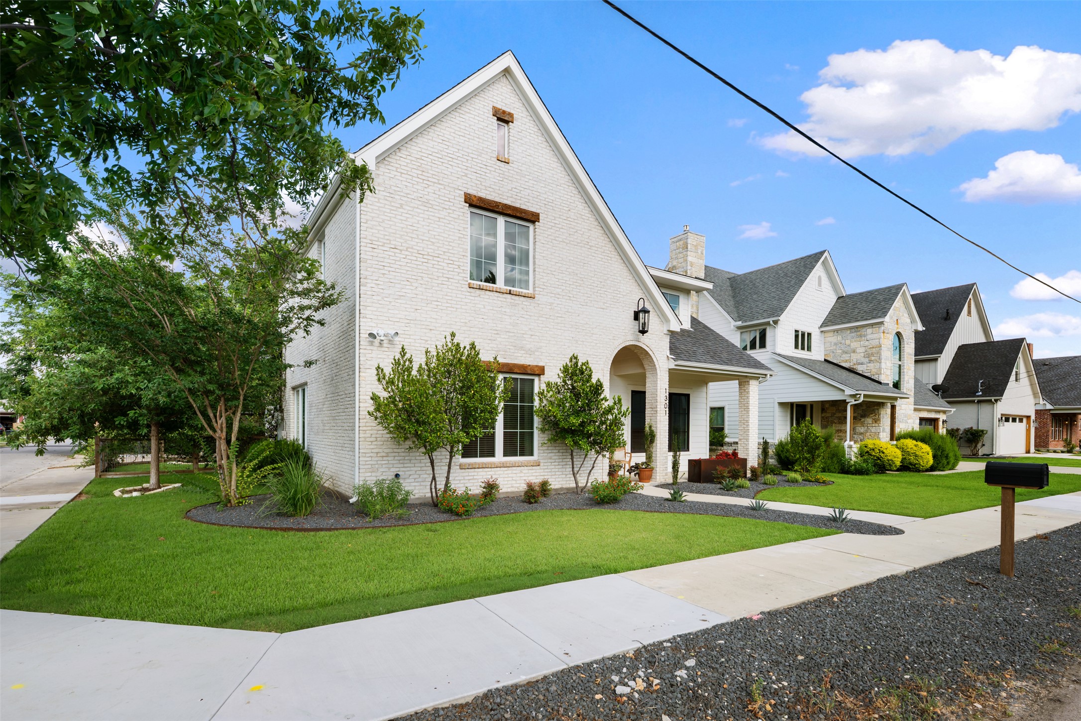 1301 West Street Georgetown, TX 78626 - Photo 2 of 40 A charming facade with white brick, arched entryway, and meticulous landscaping welcomes all.