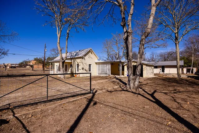 a view of a house with large tree and wooden fence
