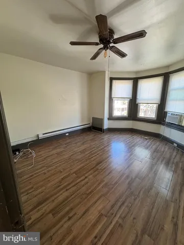 a view of an empty room with a window and wooden floor
