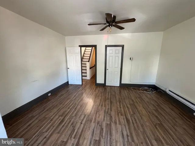 a view of empty room with wooden floor and ceiling fan