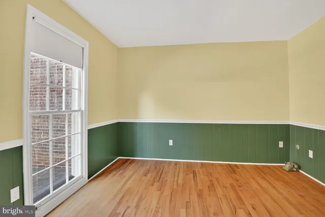 an empty room with wooden floor fireplace and windows