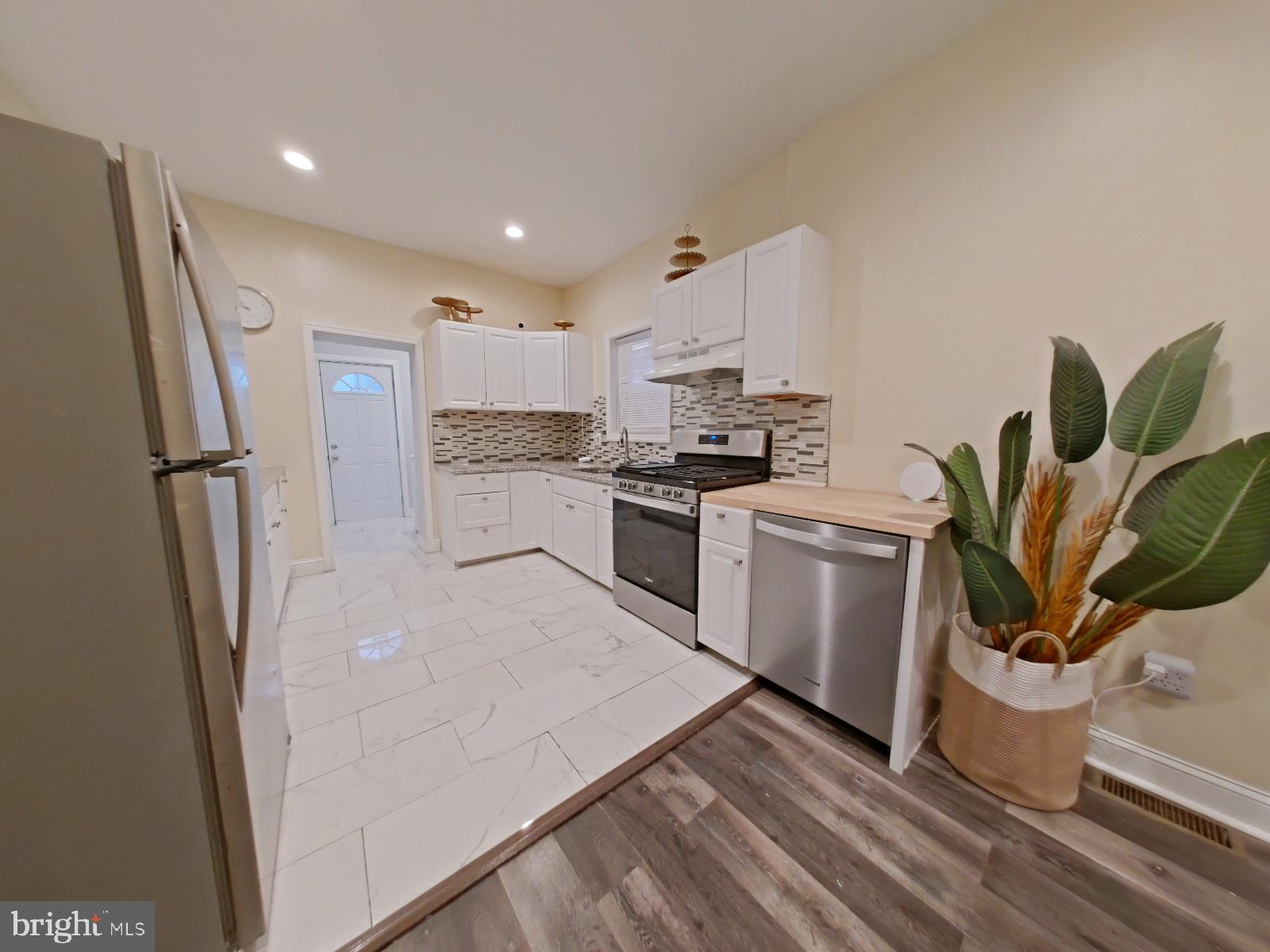 154 North 60th Street Philadelphia, PA 19139 - Photo 12 of 40 a kitchen with white cabinets and stainless steel appliances
