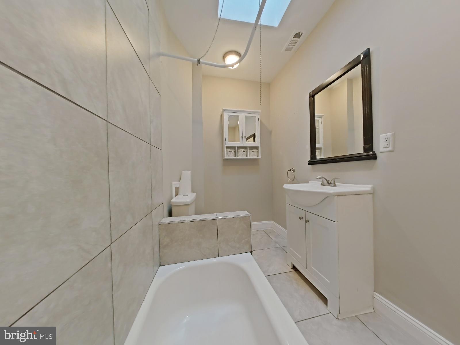154 North 60th Street Philadelphia, PA 19139 - Photo 27 of 40 a bathroom with a bathtub sink vanity and mirror