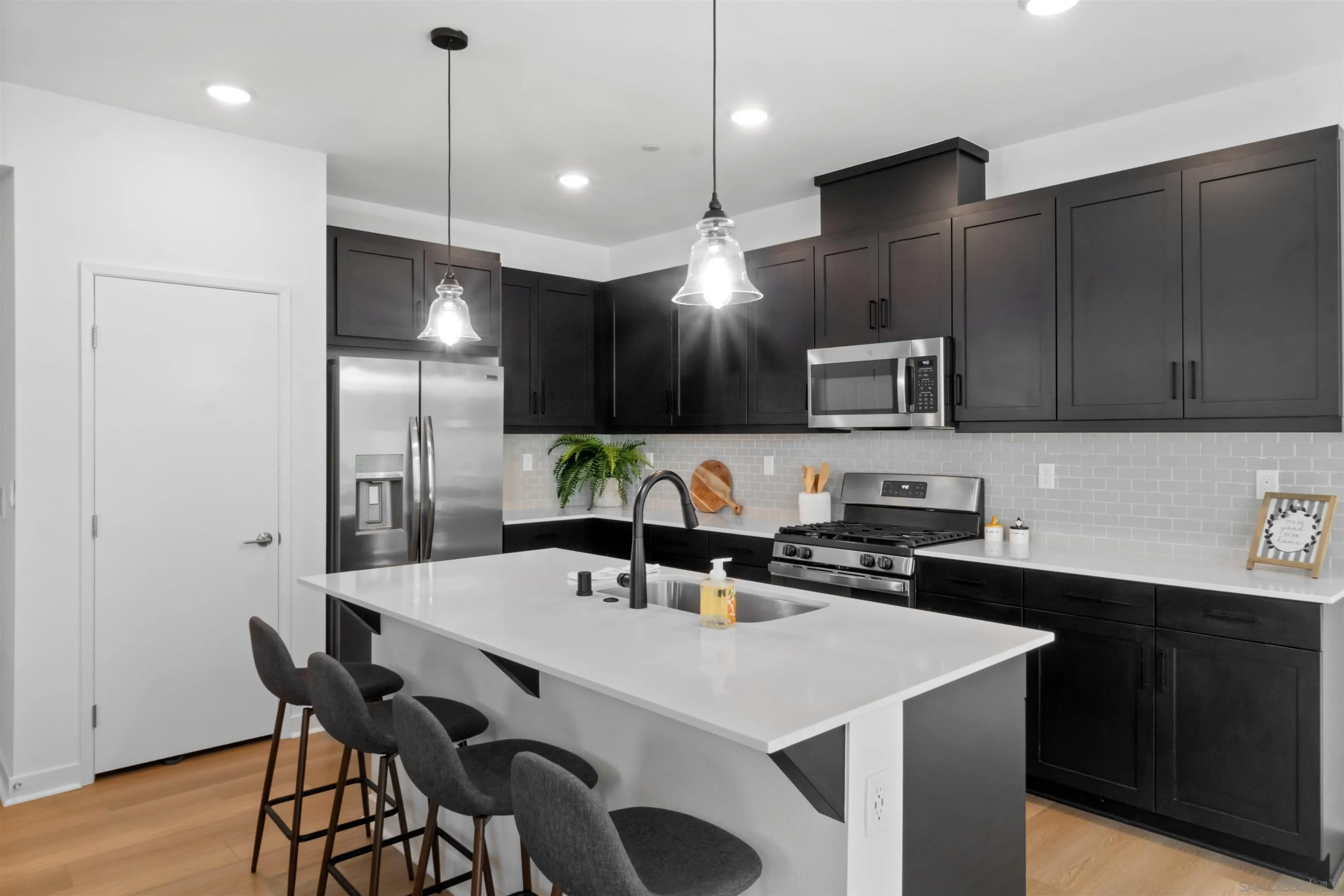 211 Canopy Trails Place Fallbrook, CA 92028 - Photo 6 of 29 a kitchen with stainless steel appliances a dining table chairs refrigerator and microwave