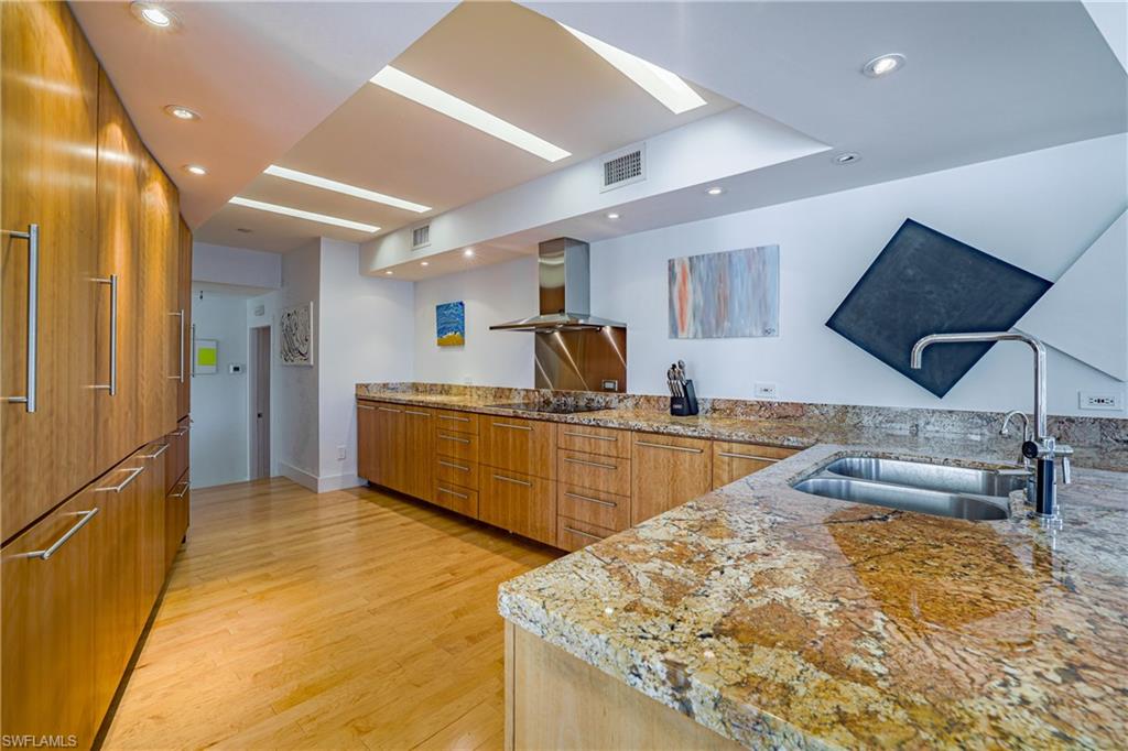 536 Turtle Hatch Road Naples, FL 34103 - Photo 11 of 28 Kitchen featuring brown cabinetry, light stone countertops, modern cabinets, wall chimney exhaust hood, and recessed lighting