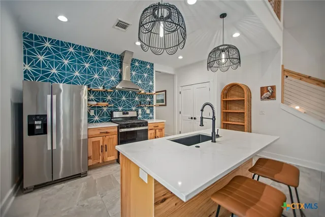 a kitchen with stainless steel appliances granite countertop a table chairs and entryway