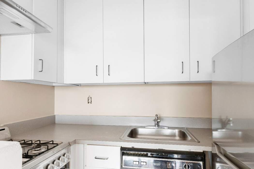 23-22 30th Road, Unit 10H Queens, NY 11102 - Photo 6 of 16 a kitchen with white cabinets and appliances