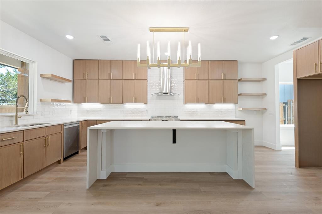 3913 Blue Ridge Boulevard Dallas, TX 75233 - Photo 9 of 25 Modern kitchen featuring a large central island, light wood-finish cabinetry, white subway tile backsplash, and wood-finish flooring