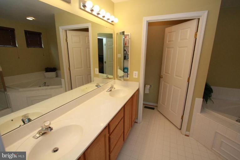 14418 Autumn Crest Road Boyds, MD 20841 - Photo 23 of 26 a bathroom with a double vanity sink a mirror and a bathtub