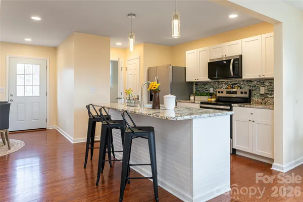 a kitchen with stainless steel appliances a microwave a stove a sink a dining table and chairs