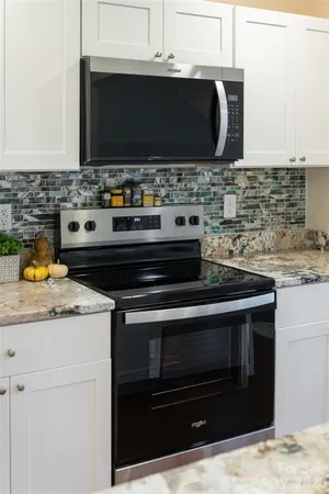 a kitchen with granite countertop a stove and a microwave