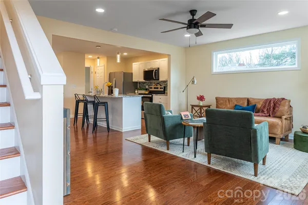 a living room with furniture a flat screen tv and kitchen view