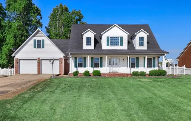 a front view of a house with a garden and trees