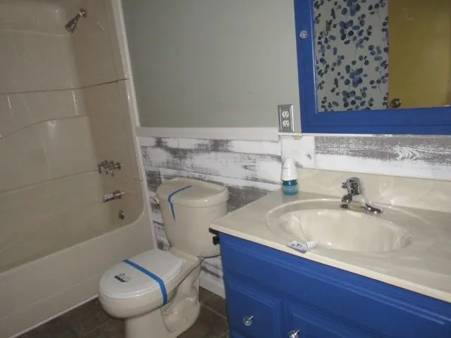 a bathroom with a granite countertop sink a toilet and bathtub