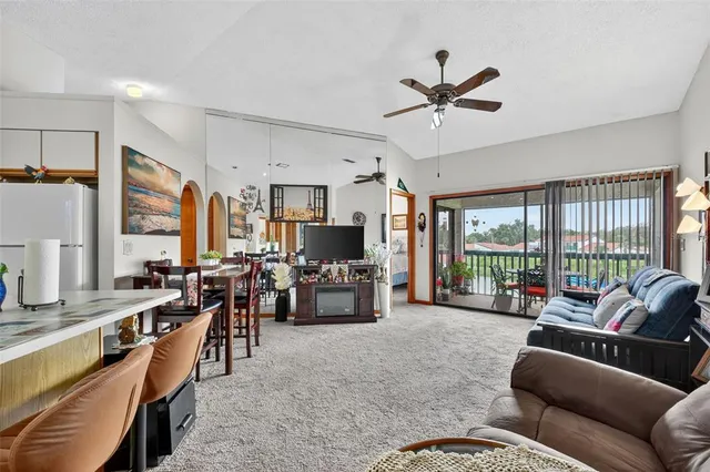 a living room with furniture kitchen view and a large window
