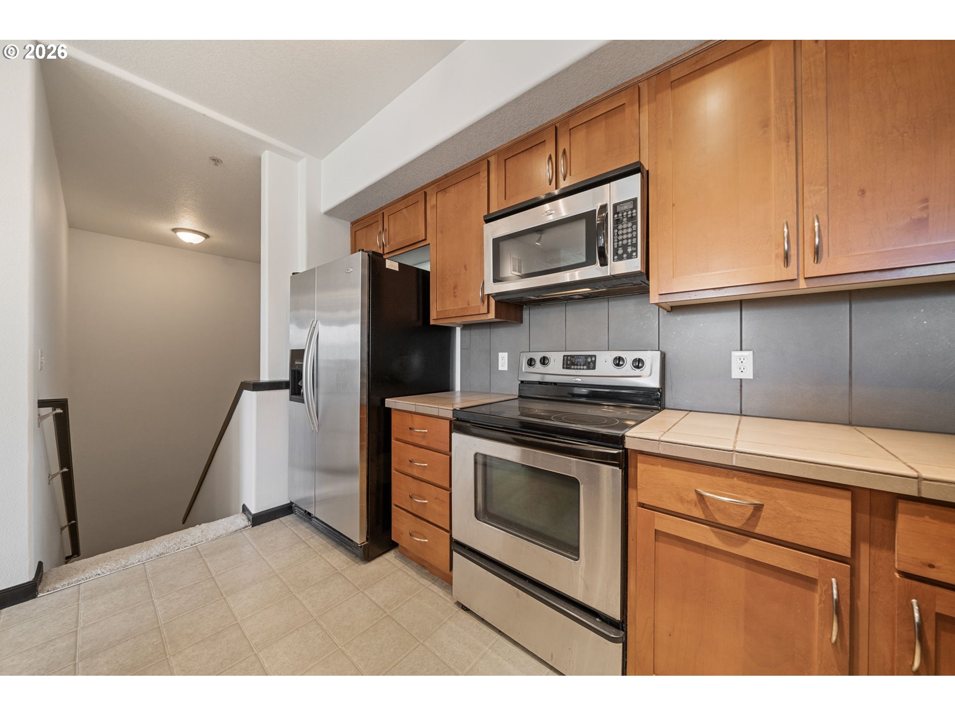 695 Northwest Falling Waters Lane, Unit 304 Portland, OR 97229 - Photo 12 of 25 a kitchen with stainless steel appliances granite countertop a refrigerator a stove and a sink with cabinets