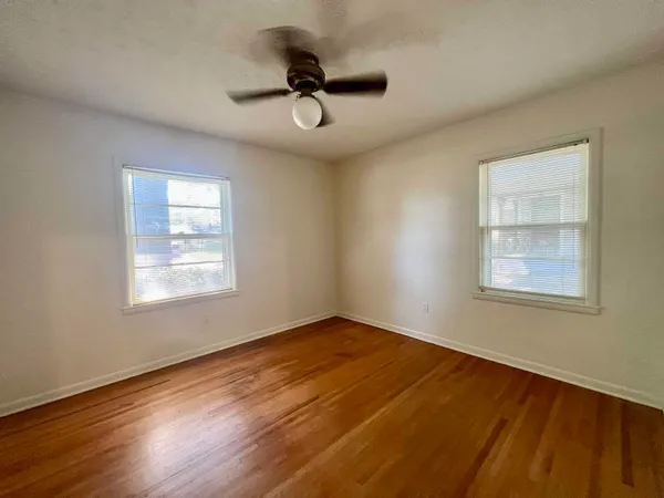 a view of empty room with wooden floor and fan