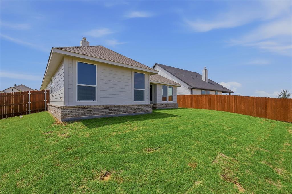 1201 Colca Drive Springtown, TX 76082 - Photo 31 of 32 Expansive backyard with a full privacy fence, manicured lawn, and brick and siding exterior