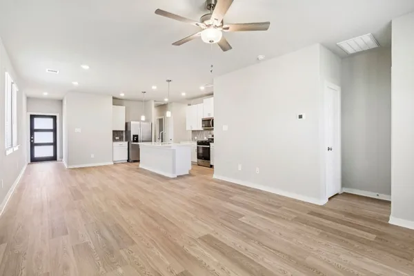 a view of a kitchen with a kitchen island wooden floor and a ceiling fan