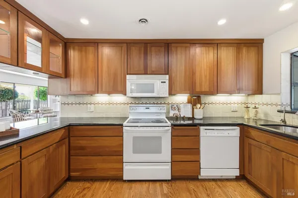 a kitchen with a stove white cabinets and sink
