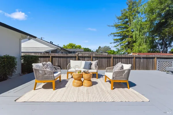 a view of a patio with couches and table and chairs with wooden floor and fence