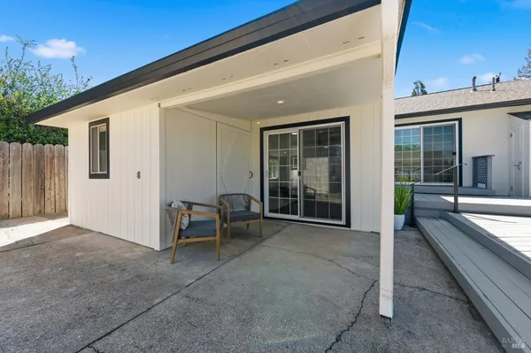 a view of a patio with table and chairs and floor to ceiling window with wooden fence