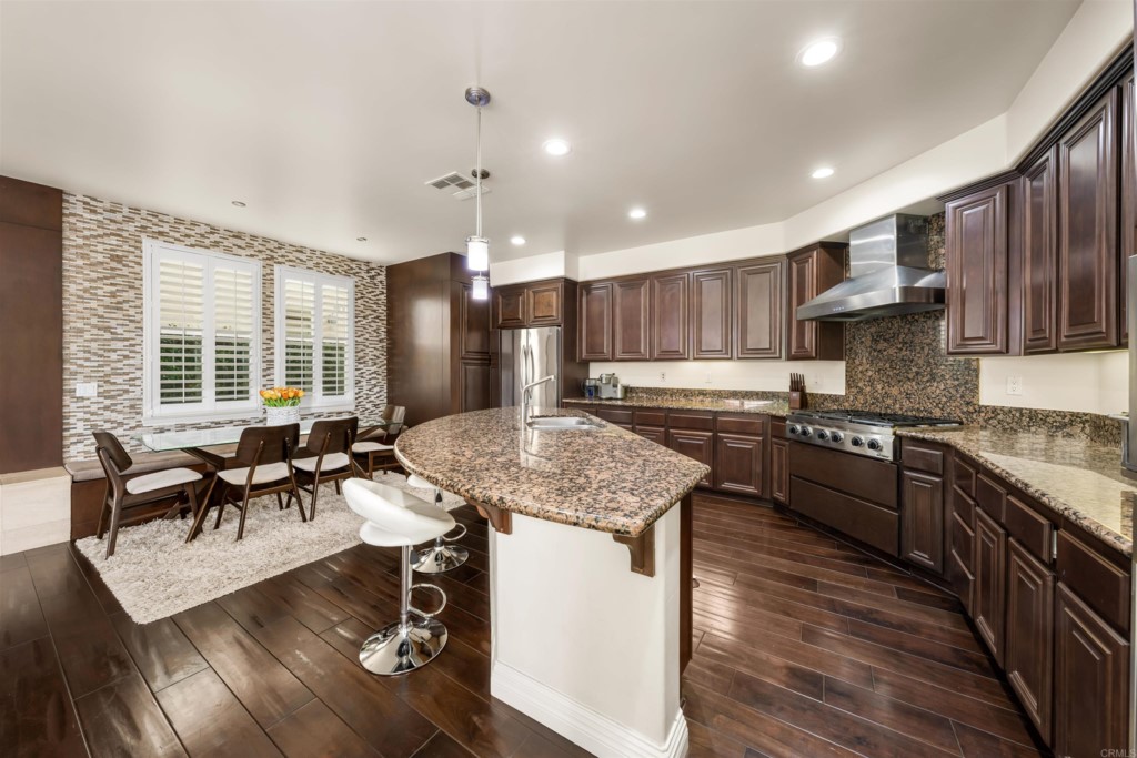 1931 Corte Cantante Chula Vista, CA 91914 - Photo 17 of 61 a kitchen with granite countertop kitchen island stainless steel appliances a stove a sink a oven a dining table and chairs