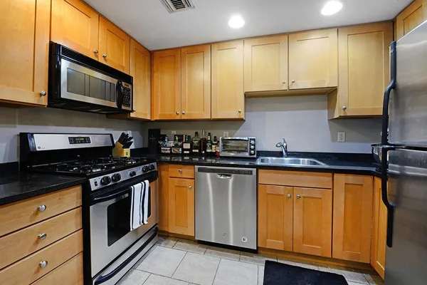 a kitchen with stainless steel appliances granite countertop a stove a sink and a microwave