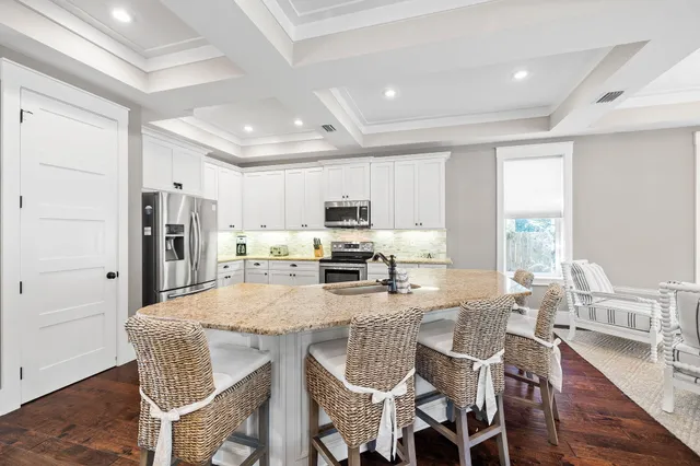 a dining room with stainless steel appliances kitchen island granite countertop a dining table chairs and a refrigerator