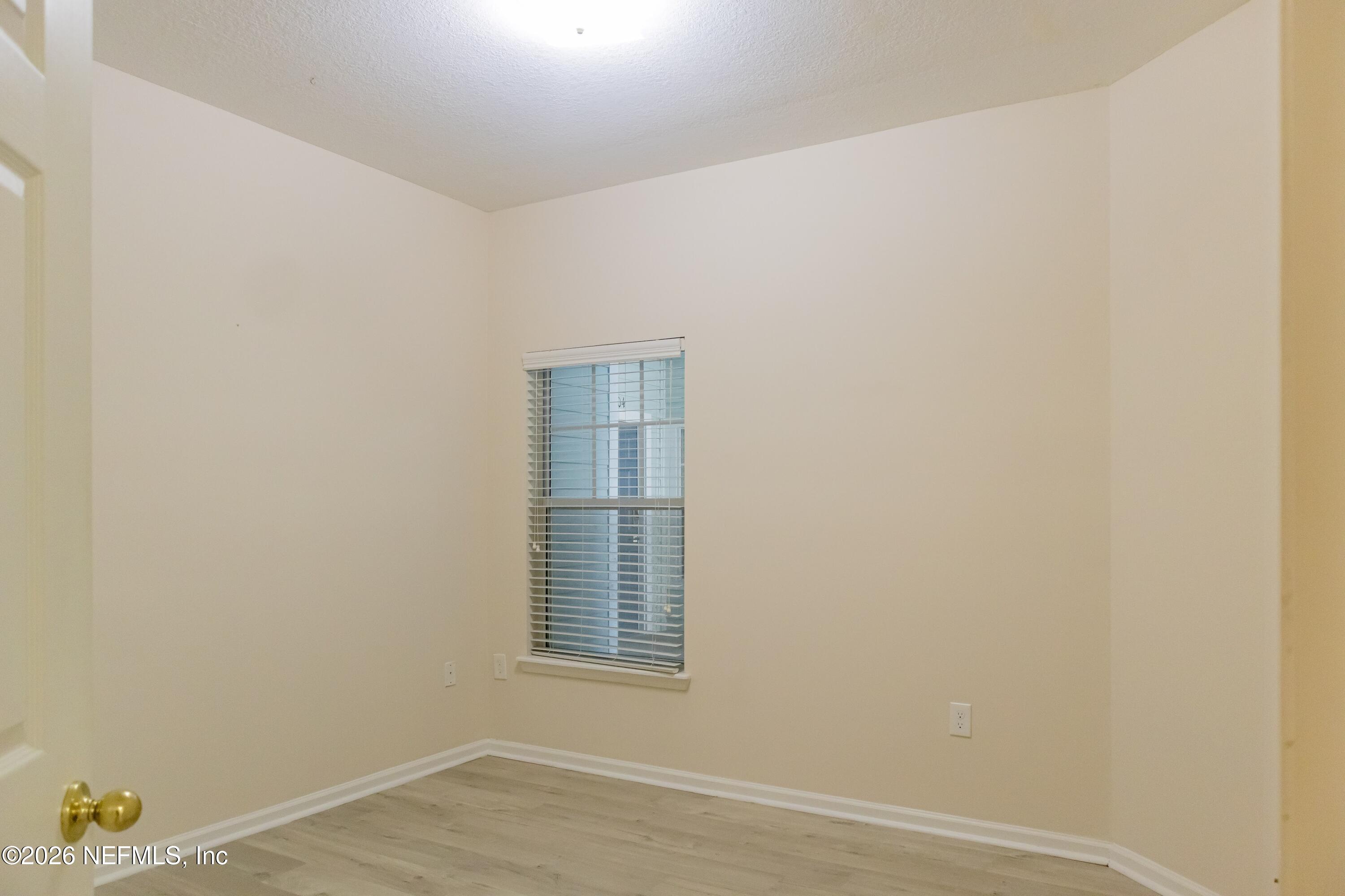 8226 Green Parrot Road, Unit 105 Jacksonville, FL 32256 - Photo 4 of 17 a view of an empty room with wooden floor and a window