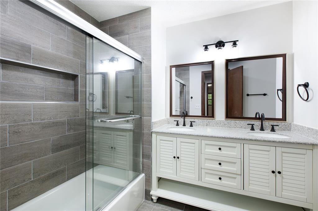 6464 Westerly Way Douglasville, GA 30135 - Photo 12 of 40 a bathroom with a double vanity sink a large mirror and a bathtub