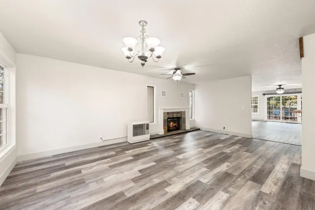 a view of a livingroom with a fireplace a chandelier and windows