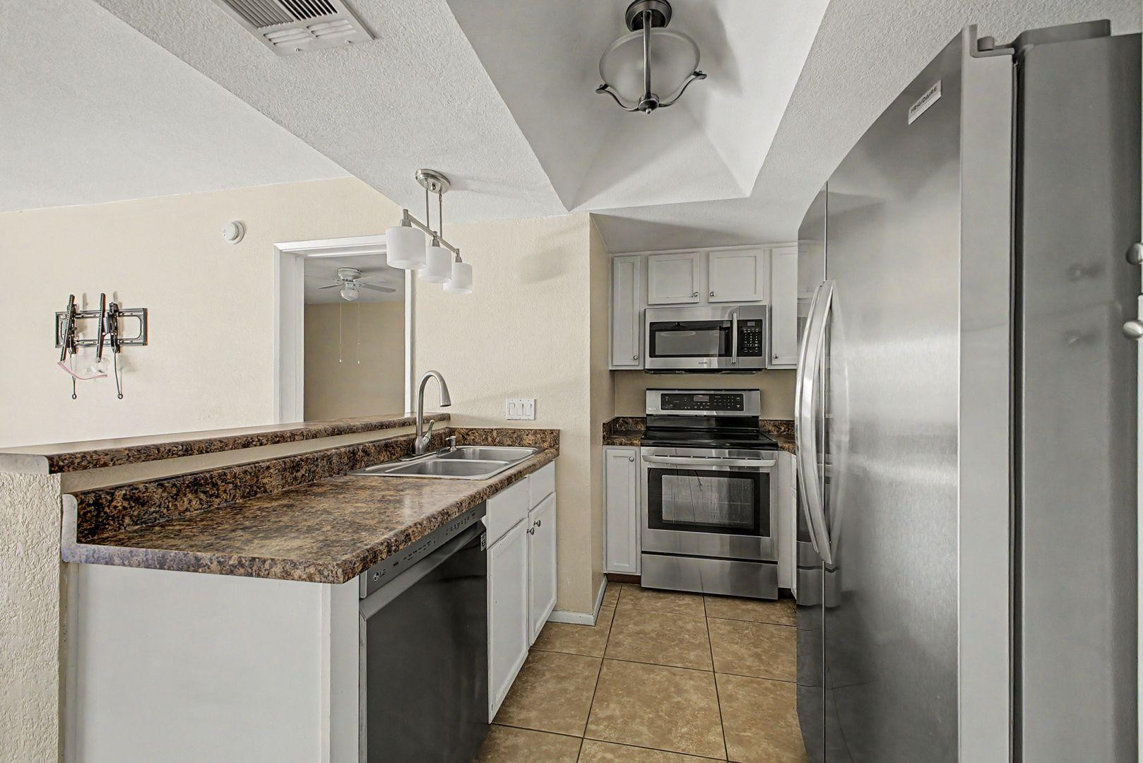 1720 East Thunderbird Road, Unit 1086 Phoenix, AZ 85022 - Photo 7 of 32 a kitchen with stainless steel appliances granite countertop a sink and a refrigerator