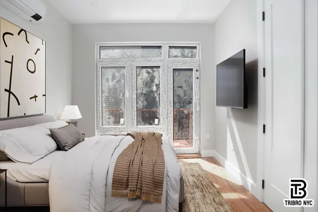 a bedroom with a bed and a flat tv screen on dresser