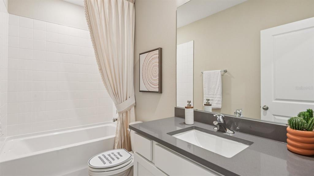32511 Welling Blade Loop Wesley Chapel, FL 33545 - Photo 28 of 42 a bathroom with a granite countertop sink toilet a mirror and bathtub