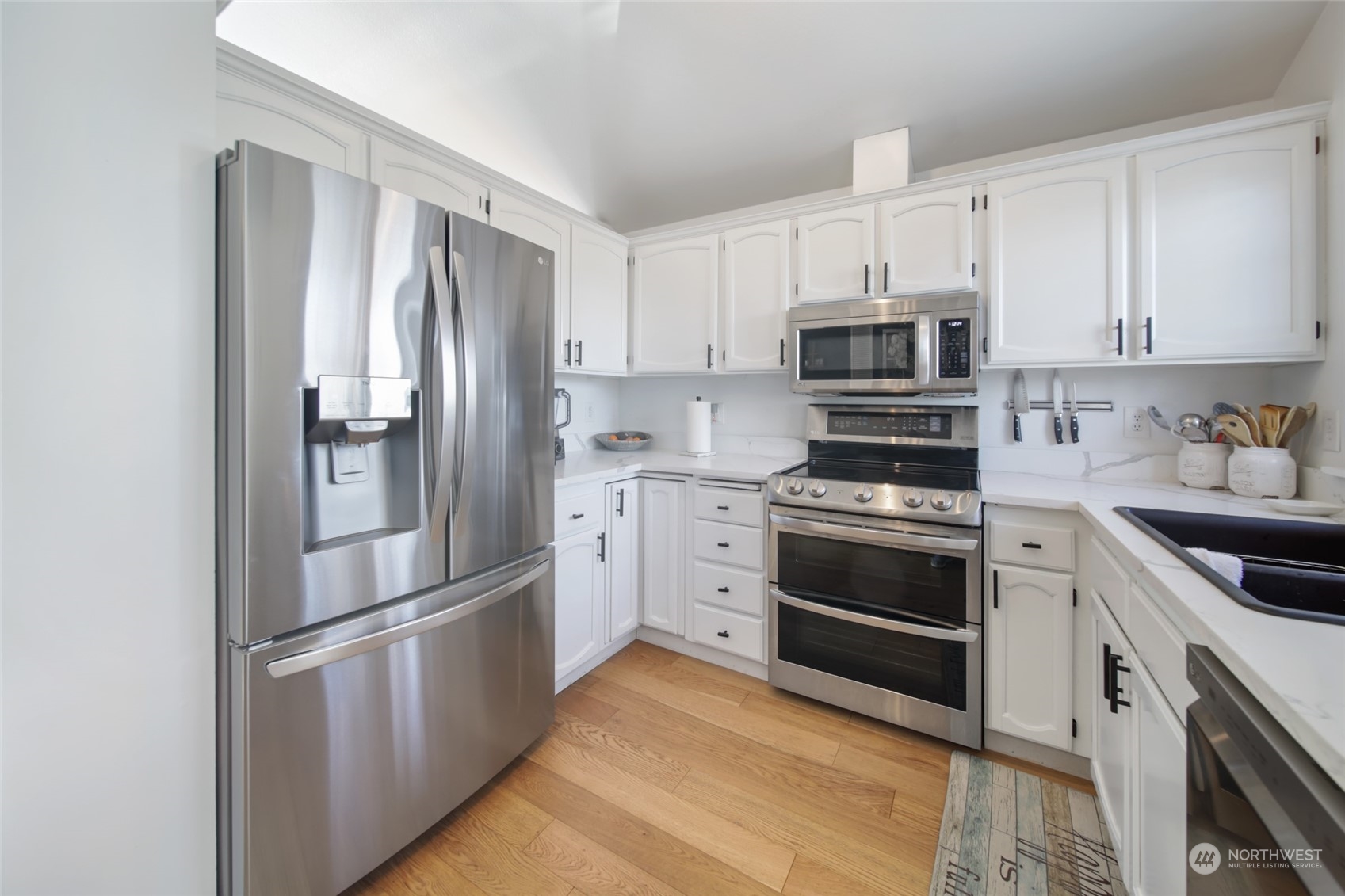 1663 South 48th Street Tacoma, WA 98408 - Photo 4 of 25 a kitchen with cabinets stainless steel appliances and wooden floor