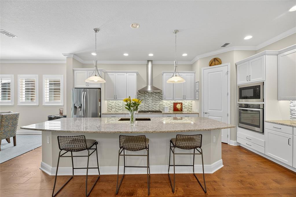 6002 Sparrowhead Way Lithia, FL 33547 - Photo 2 of 55 a kitchen with stainless steel appliances kitchen island granite countertop a dining table chairs refrigerator and microwave