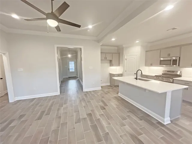 a large white kitchen with kitchen island a sink stainless steel appliances and cabinets