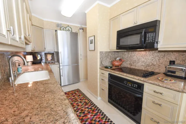 a kitchen with granite countertop a sink stove and refrigerator