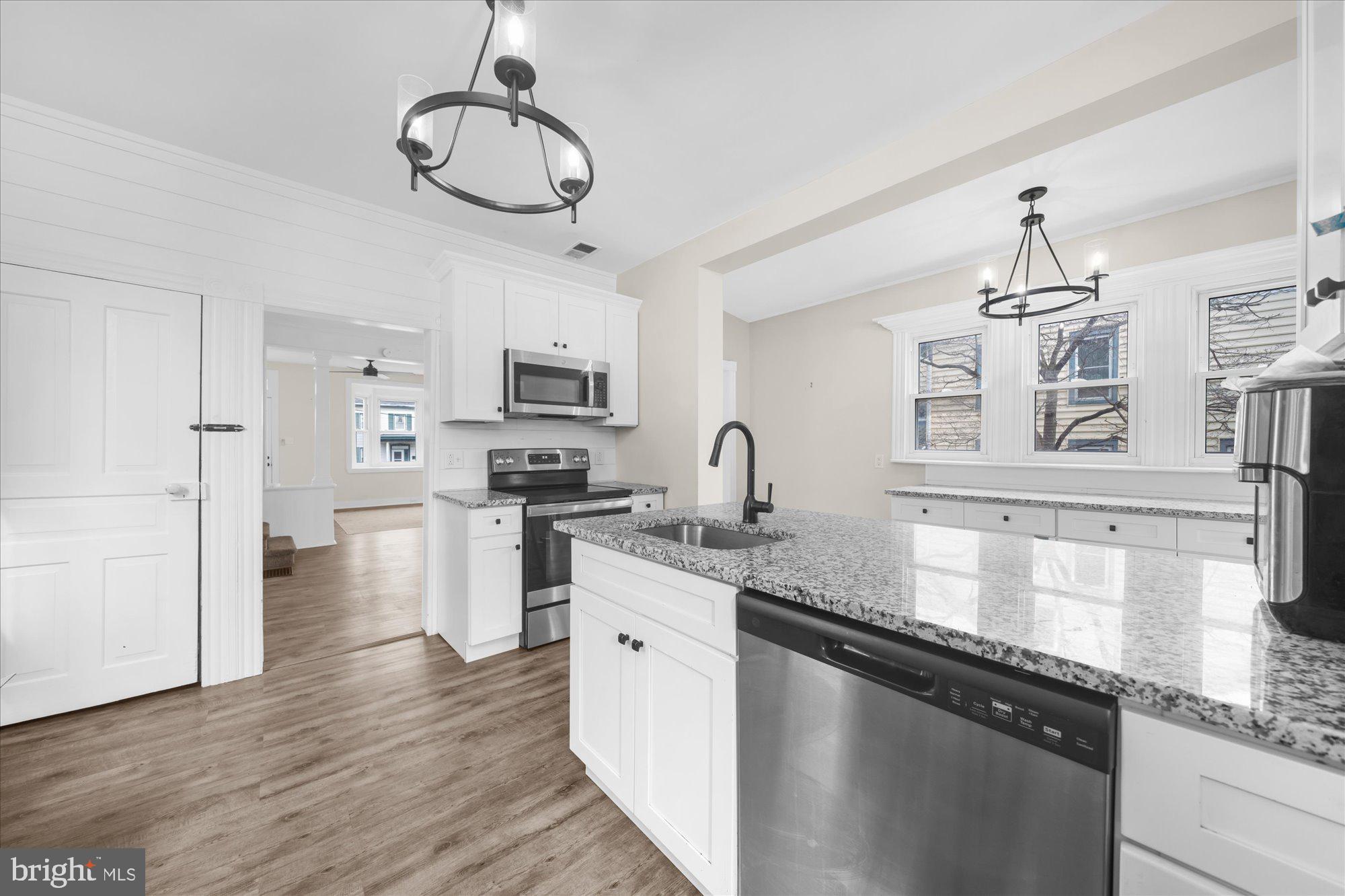 109 New Holland Avenue Reading, PA 19607 - Photo 12 of 36 a kitchen with stainless steel appliances granite countertop a sink refrigerator stove and white cabinets with wooden floor